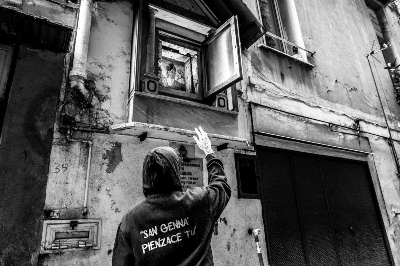 Devoto diante de um nicho votivo de San Gennaro em Nápoles, fotografia de Giuseppe Troisi